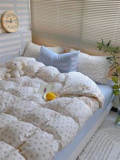 a bed that has some pillows on it and a teddy bear sitting on the pillow