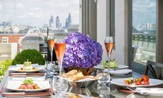 the table is set with food and drinks on it, overlooking the cityscape