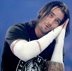 a man with long hair and white gloves on his arm is posing for a photo