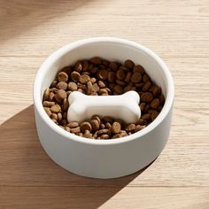 a white dog bone in a bowl filled with coffee beans on top of a wooden table