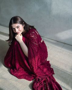 a woman sitting on the floor in a red dress with her hand under her chin