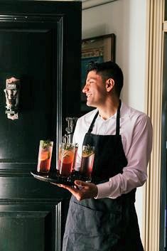 a man in an apron holding some drinks