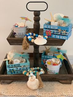 three tiered tray with shells, seashells and other items on the table