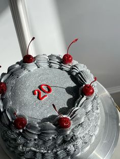 a silver cake with cherries on it and the number twenty nine in red is sitting on a table