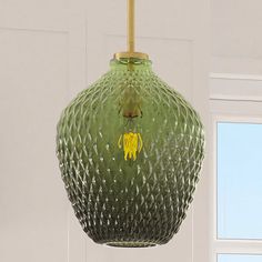 a green glass light fixture hanging from a ceiling in a room with white walls and windows