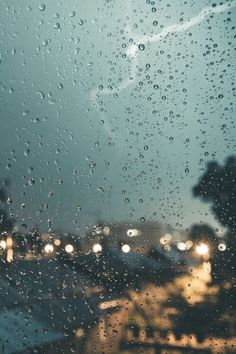 rain is falling down on the windshield of a car