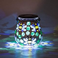 a colorful glass jar sitting on top of a table next to a black light bulb