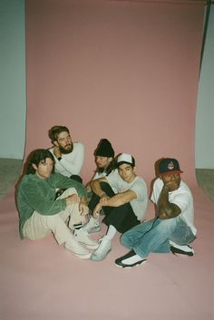 five young men sitting in front of a pink wall