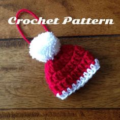 a red and white crochet hat on top of a wooden table