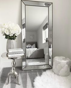 a mirror sitting on top of a table next to a vase filled with white flowers