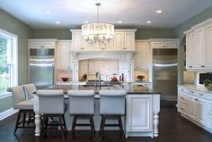 a large kitchen with white cabinets and an island in the middle is surrounded by bar stools