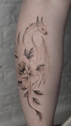 a woman's leg with flowers and a dragon tattoo on it