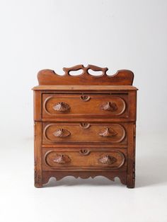 an old wooden dresser with four drawers and knobs on the bottom drawer, against a white background