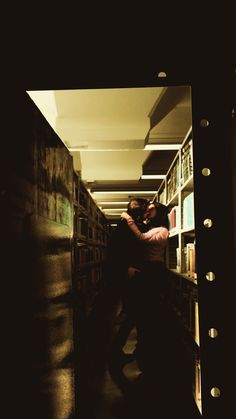 two people hugging each other in front of bookshelves