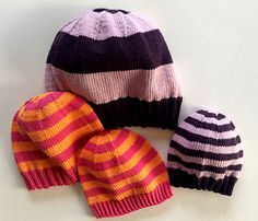 three knitted hats sitting next to each other on top of a white countertop