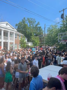 a large group of people standing in front of a building with a basketball hoop above them