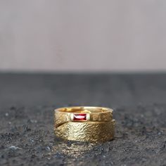 a close up of a gold ring with a red stone in the center on a black surface