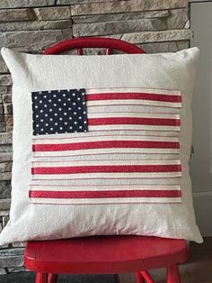 an american flag pillow on a chair in front of a brick wall with a fire hydrant