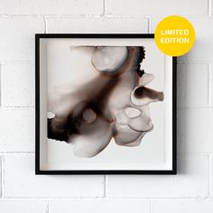 a black and white photograph hanging on a brick wall next to a framed print with an abstract design