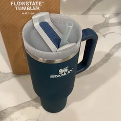 a blue travel mug with two toothbrushes in it and a box on the table