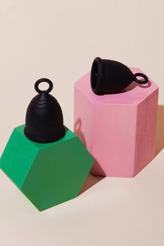 two different colored objects sitting next to each other on a white surface with one black object in the middle