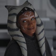 a close up of a person wearing a cat mask with stripes on their face and hood