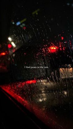 rain drops on the windshield of a car at night with an inspirational quote written in it