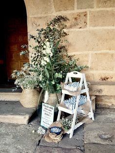 a display of flowers and candles on the side of a building next to a potted plant