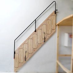 a wooden stair case sitting next to a white wall