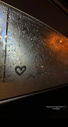 rain drops on the window of a bus with a heart drawn on it's side