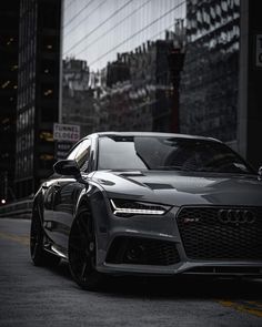 a grey car parked on the side of a road in front of some tall buildings