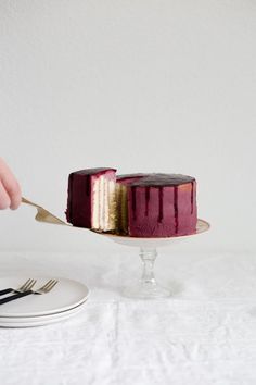 a person holding a fork over a cake on a plate