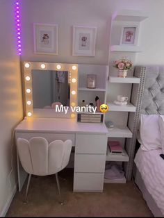 a white vanity with lights on it next to a bed and a desk in front of a mirror