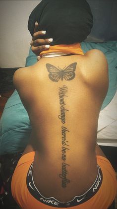 the back of a woman's body with a butterfly tattoo on her lower back