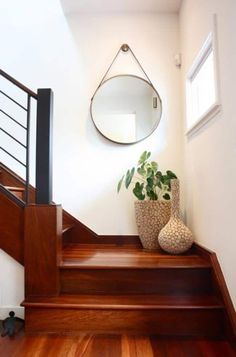 there is a plant on the stairs next to a mirror and vase with plants in it