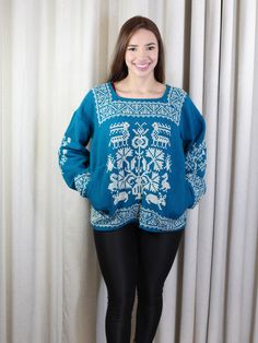 a woman standing in front of a curtain wearing black leggings and a blue sweater