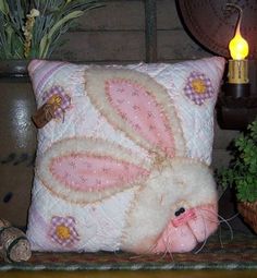 a stuffed bunny rabbit sitting on top of a pillow next to a potted plant