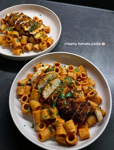 two white plates filled with pasta and meat on top of a black countertop next to each other