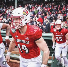 two football players in red and white uniforms are walking off the field with their helmets on