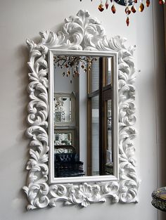 an ornate white mirror hanging on the wall