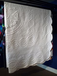 a white quilt hanging on a clothes rack in a room with blue walls and carpet