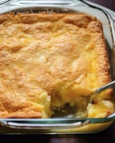 a close up of a casserole in a glass dish with a serving spoon