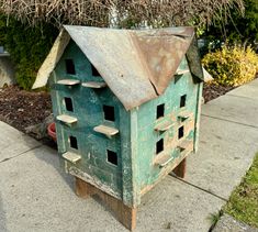 an old bird house is sitting on the sidewalk