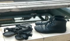 two pairs of black shoes sitting on top of a wooden bench