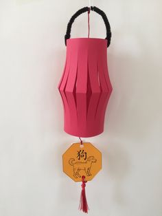 a paper lantern hanging from the ceiling with chinese writing on it and a dog tag