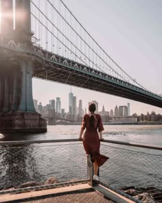 a woman in a red dress is looking at the bridge