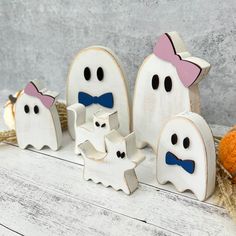 three wooden ghost figurines sitting next to each other on a white wood table