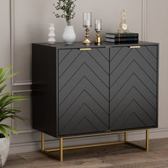 a black and gold cabinet with candles on top next to a potted green plant