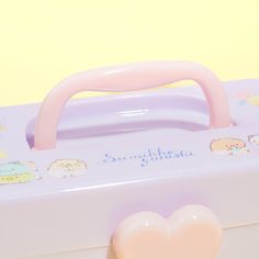 a pink heart shaped object sitting on top of a white suitcase with hello kitty stickers