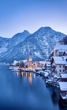 a snowy town on the shore of a lake with mountains in the backgroud